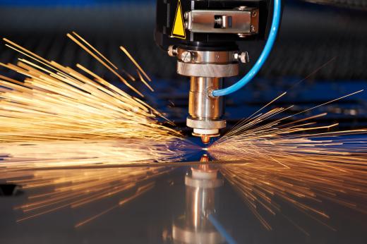 A laser cutter is used to cut a sheet of metal. Software is typically used to control the beam.