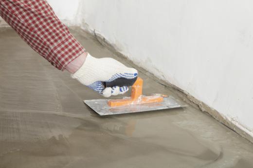 A man smoothing out hydraulic cement on a basement floor.