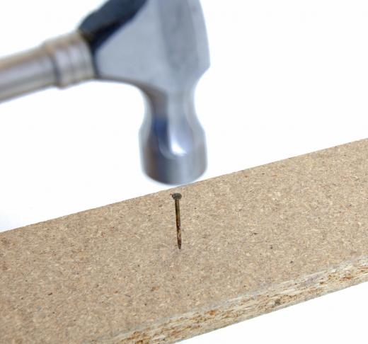 A nail being driven into a piece of engineered wood.