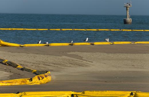 Oil booms being used to contain an oil spill. Clumps of oil in the ocean are called tarballs.