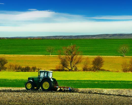 A farmer uses a tractor to pull a cultivator.