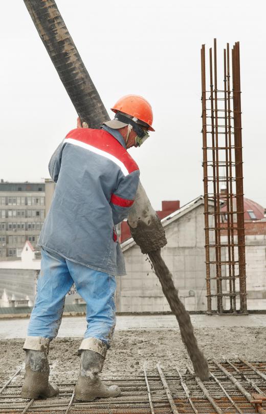 Worker pouring concrete from vibrator.